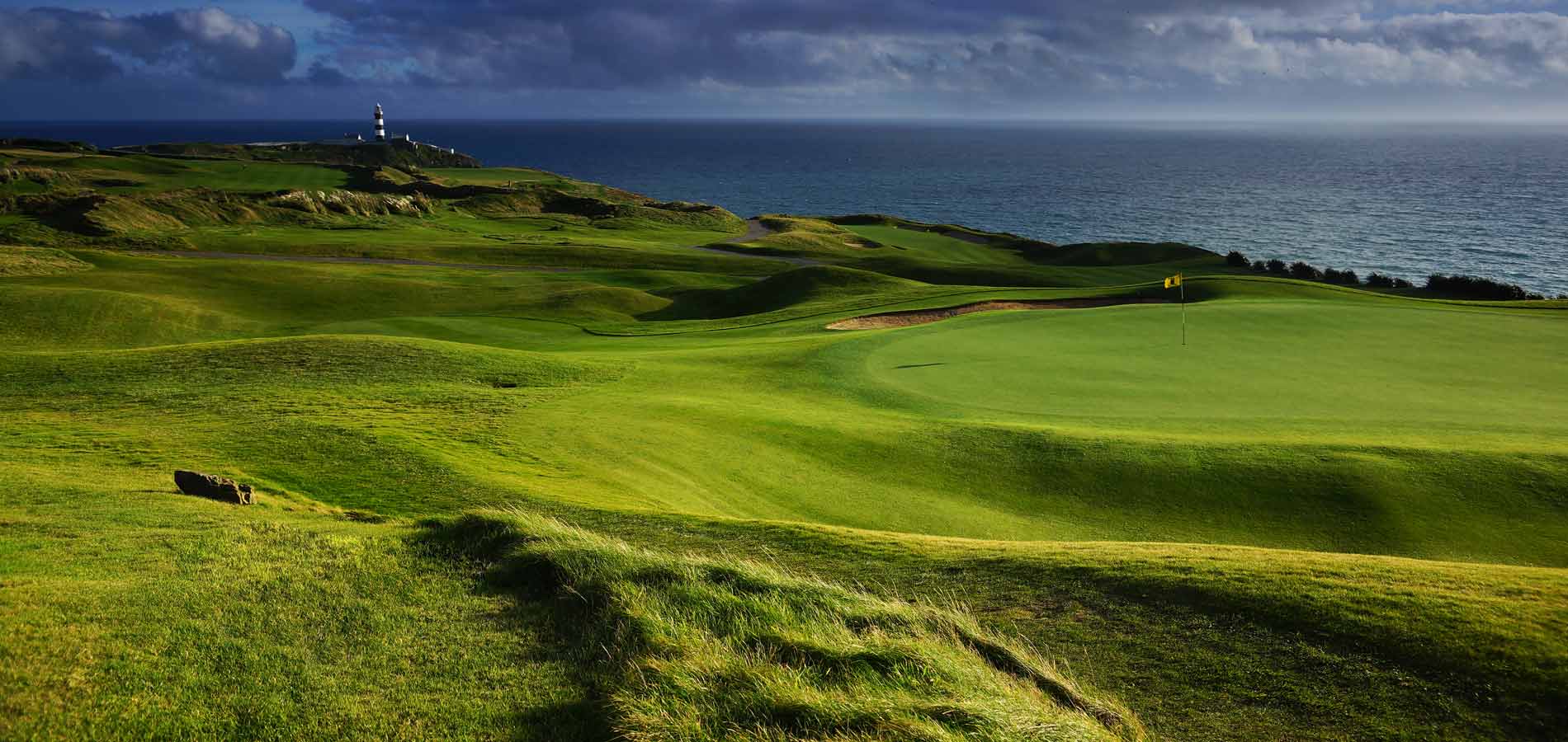 Sunlight across the green fairways and coastal dunes at Old Head